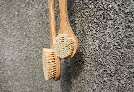 Wooden brushes with natural bristles weigh on a concrete gray background. Zero waste concept
