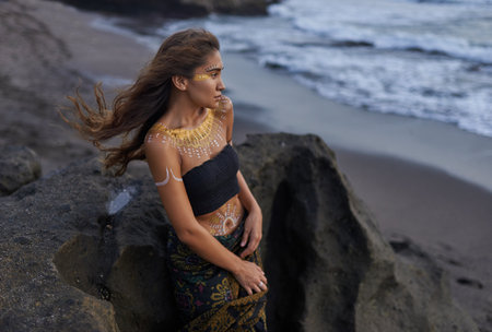 Portraits of young woman with tribal patterns covering her body, wild and beautiful, sea, sand, blackの写真素材