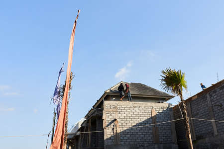 Workers put the roof shingles. Builders in the tropicsの写真素材