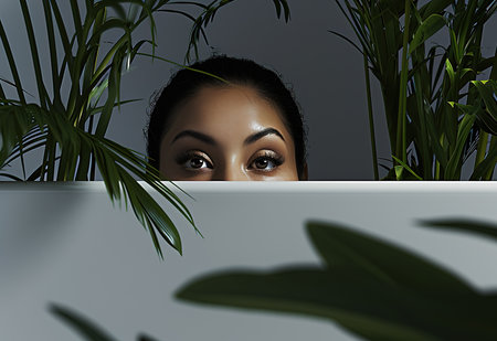 A mysterious figure hidden by lush greenery: a concept image illustrating intrigue and curiosityの素材