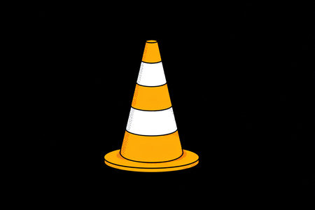 A bright orange traffic cone is displayed against a dark background, commonly used to signal caution and ensure safety in construction zones or road work areas.の素材