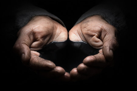 Two hands gently cradle a dark stone in a low-light environment, reflecting themes of care and protection. The scene conveys a deep sense of intimacy and connection.の素材