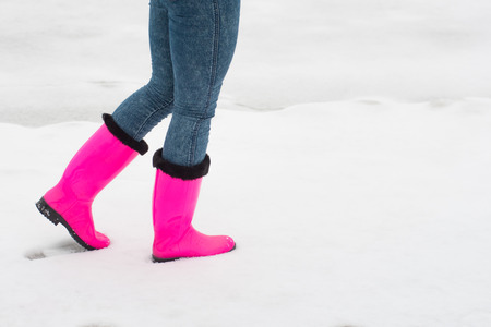 woman in red rubber boots walking on snowの写真素材