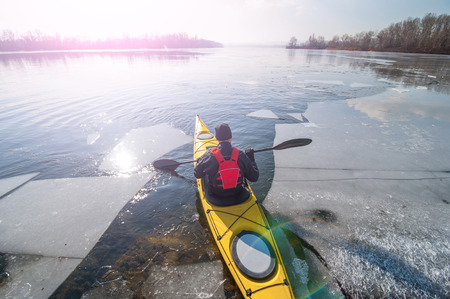 man kayak is on a frozen riverの写真素材