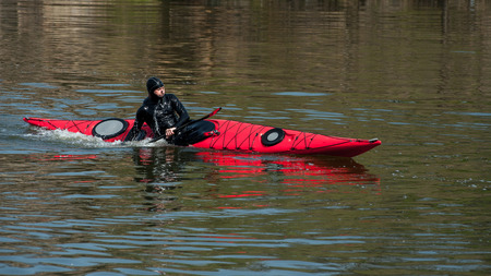 man paddles a red kayak on the river near the shore, kayakingの写真素材