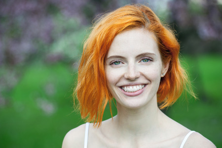 closeup portrait of a happy beautiful young redhead woman with adorable smile, green eyes and...