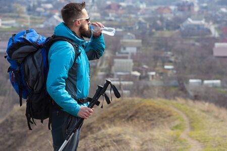 man tourist on the top of the hill stood drinking water while travelingの写真素材