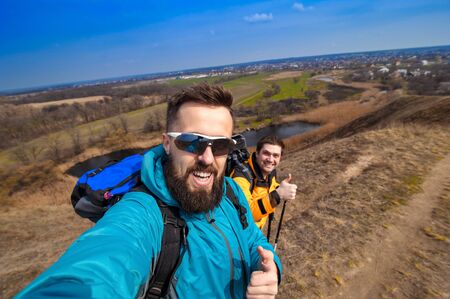 male with friend hiker taking photo with smartphone in forest, looking at camera, copy space for...
