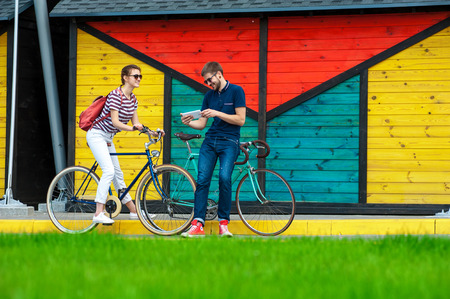 young cheerful couple on bicycles looking into the smart phone, download photos takenの写真素材
