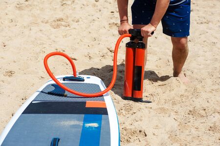 man inflates a rubber board on the beach SUPの写真素材