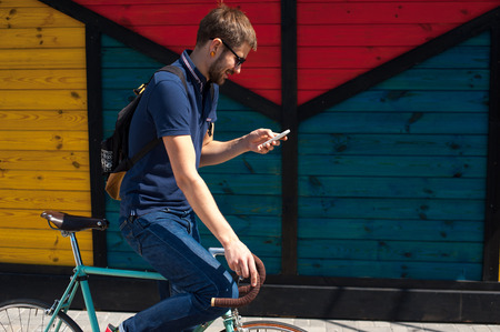 young funny man with a hire bike checking her phone, space for textの写真素材
