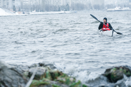 man kayaking on a winter river, extreme sports