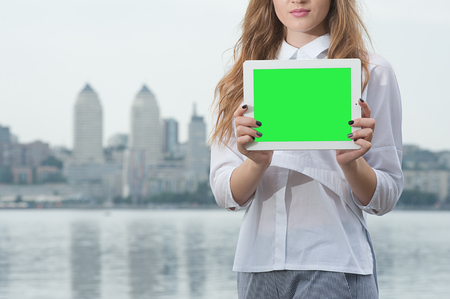 woman showing blank black smart phone screen close up, over city backgroundの写真素材