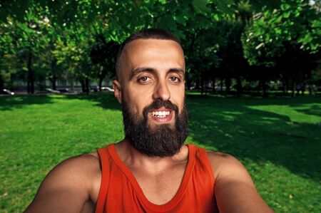 bearded man smiling looking at camera take photo with wide angle camera, self portrait pictureの写真素材