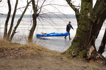 a man in a black suit walks along a frozen riverの写真素材