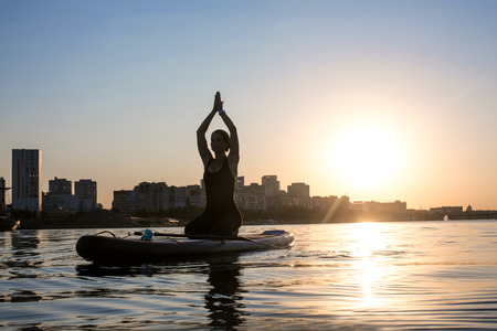 silhouette of a slender girl engaged in yoga on a city background