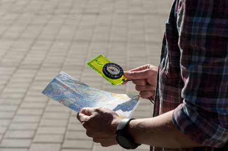 male tourist with a backpack looking map and compass