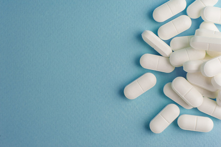 White medicine capsules on a blue background
