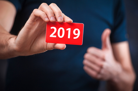 Young bearded man holds a business card with the inscription: 2019の写真素材