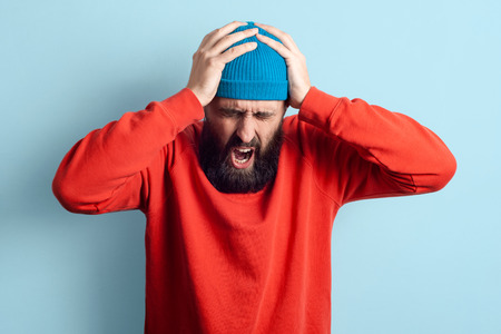 Frustrated man with raised hand isolated on blue background.の写真素材