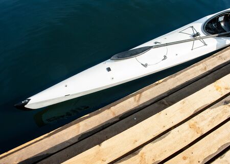Cropped close-up photo of sportive boat. Top view of professional speed canoe placed near boardwalk pierの写真素材