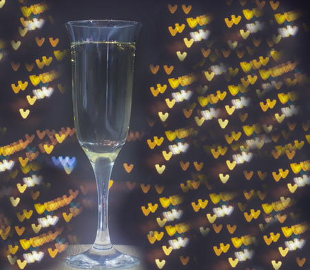 glass of champagne on bokeh background.glass with a thin stem for champagne on the background of bokeh hearts.の写真素材