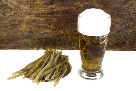 on a white background, there are sliced fish strips and a beer mug with beer and foam.の写真素材