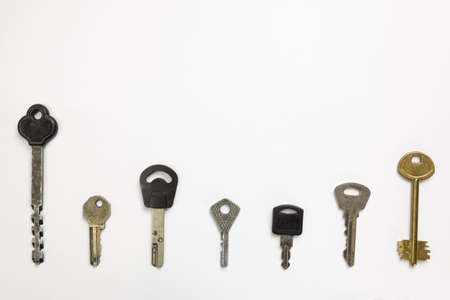 Seven types of differently shaped door keys lie in a row on a white background under clippingの写真素材
