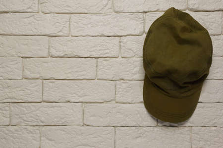The green cap hangs on a decorative light-colored brick wall on the right side. On the left side of...