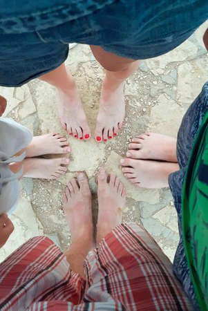 Four pairs of legs of people of different ages and genders are shot from above in the summerの写真素材