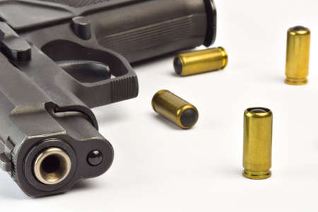 Traumatic pistol with barrel in frame close-up and several cartridges on white clipping background