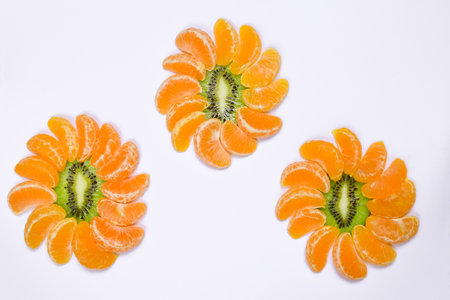 Three decorative forms in the form of flowers are laid out from slices of tangerine and kiwi