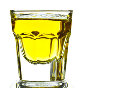 On a white background on the left side of a glass with whiskey close-up. On the right is a place for an inscriptionの写真素材