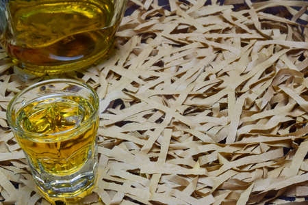 Against a background of beige ribbons on the left, there is a glass full of whiskey and a bottle. On the right is an empty space for the inscriptionの写真素材