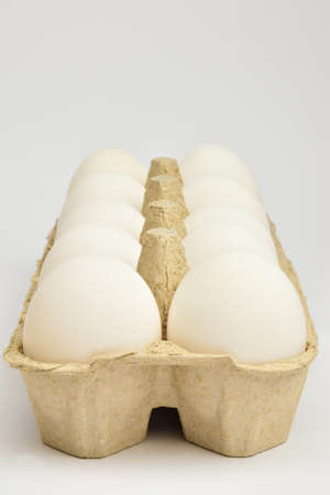 Ten chicken eggs lie in two rows in a cardboard tray. The tray lies obliquelyの写真素材