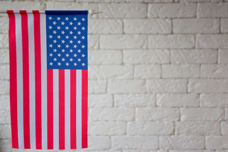 On the left side of the frame is the USA flag against the backdrop of a BLURED brick wall. On the right is an empty space to insert text. Blurred backgroundの写真素材