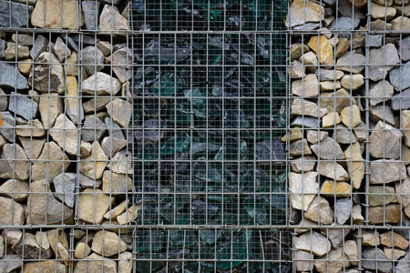 A decorative fence made of stones behind bars and broken large glass in the middle. Photographed full frameの写真素材