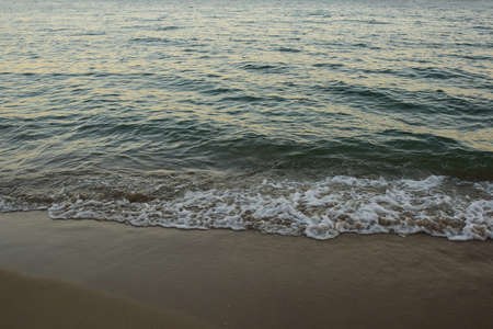 Sea waves roll on the sandy daytime beach