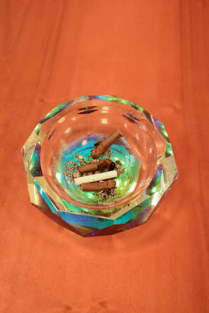 Crystal ashtray with extinct cigars on a wooden table