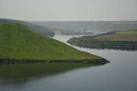 The sea fjord meanders between green grass-covered hills
