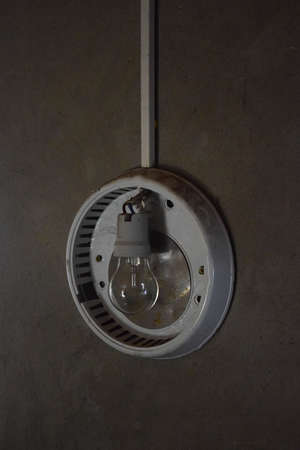 Turned off round shape lamp hanging on the wall in a dark room