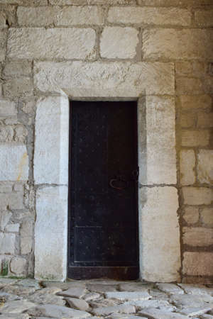 Wooden gates of an old medieval castle or fortress, covered with strips of iron. The gate has a closed wicket with a handleの写真素材