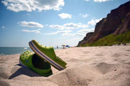 In the foreground are sandals on a sandy beach. The sea is not visible. The background is blurryのeditorial素材