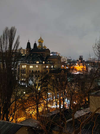 High angle view of the evening city with houses, trees and religious buildings. The sky is overcast