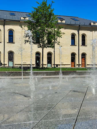 Decorative street fountains made of gray marble tiles on a city street during the day. At a short...