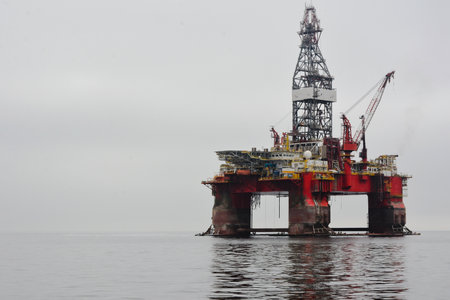 Photo of the platform oil rig placed in the ocean water on the right of the frame. On the left is a...