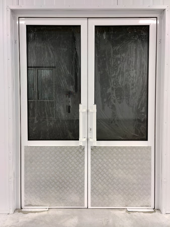 White two-way doors of a closed unbranded store with shuttered windowsの写真素材