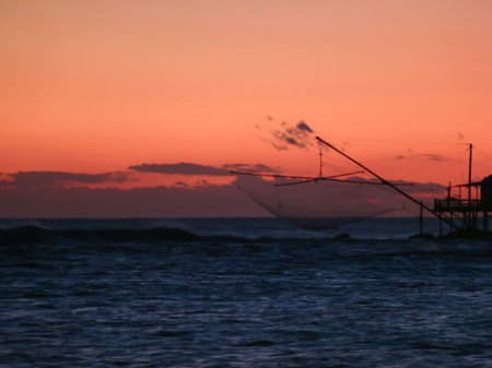 At sunset, fishermen's fishing nets hang in the sea. The background is very dark and blurryの写真素材