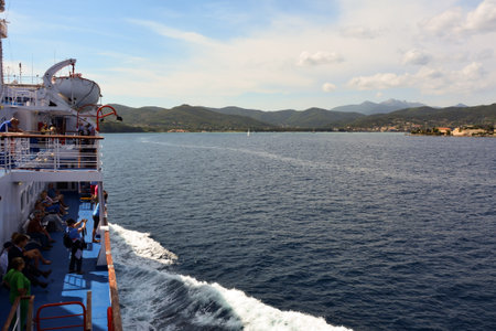 Tourists look from aboard a large sea ship at a picturesque coast with mountains and landmarks and landscapeの写真素材