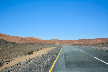Lonely empty asphalt road in the desert in perspective against a clear blue skyの写真素材